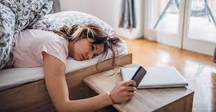 A girl touching her phone lying on her bed